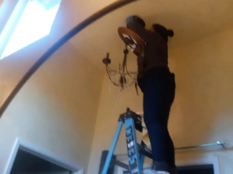 Electrician installing a chandelier in a Olney residence